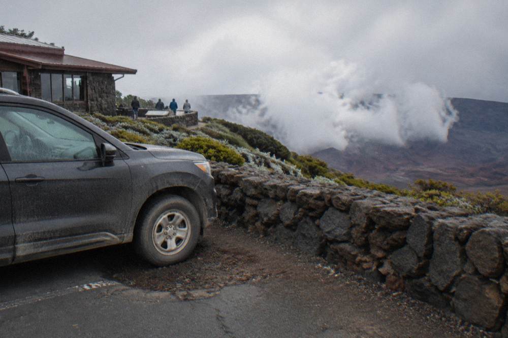 A parked car beside a crater overlook with the vast bowl of Haleakala stretching below