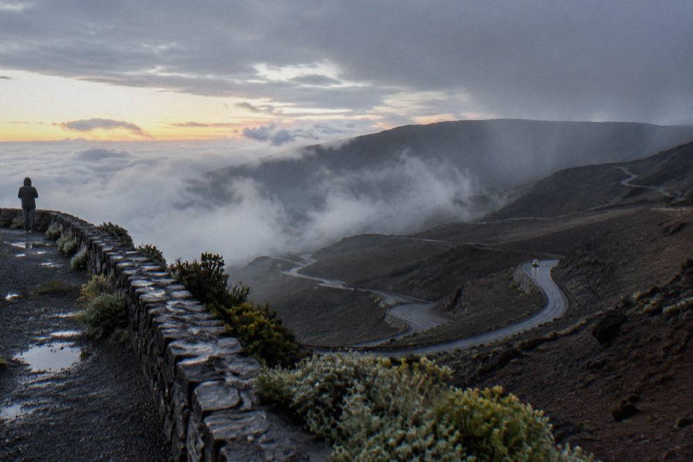 The winding park road climbing through clouds toward the Haleakala summit district at dawn