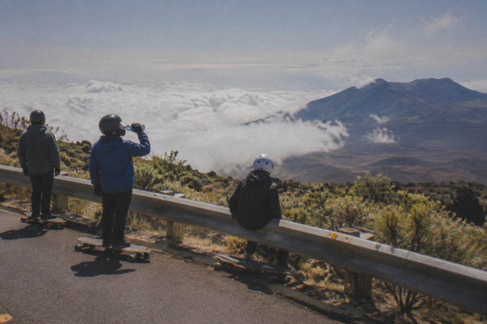 Cyclists in jackets and helmets pausing on a paved mountain road above the clouds