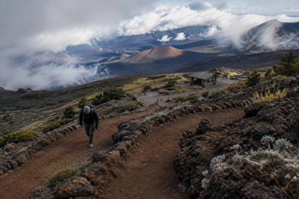 Lone hiker climbing a switchbacking cinder trail up the inner wall of the Haleakala crater