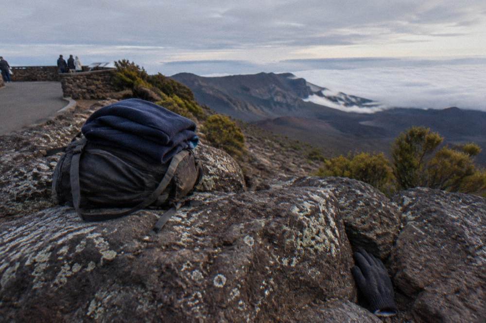 Backpack and layered clothing resting on a rock above the clouds at a Haleakala overlook