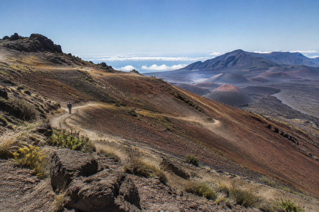 Winding trail descending into the red cinder landscape of the Haleakala crater under a wide sky