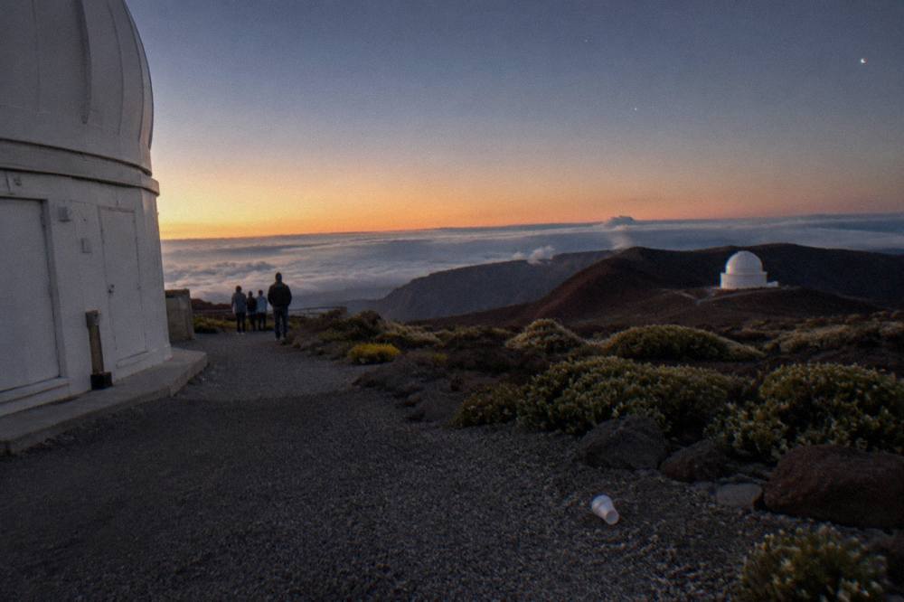 Dark summit landscape at dusk with the first stars appearing over the crater rim