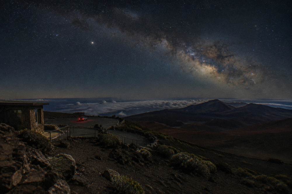Milky Way arching over a dark volcanic summit landscape