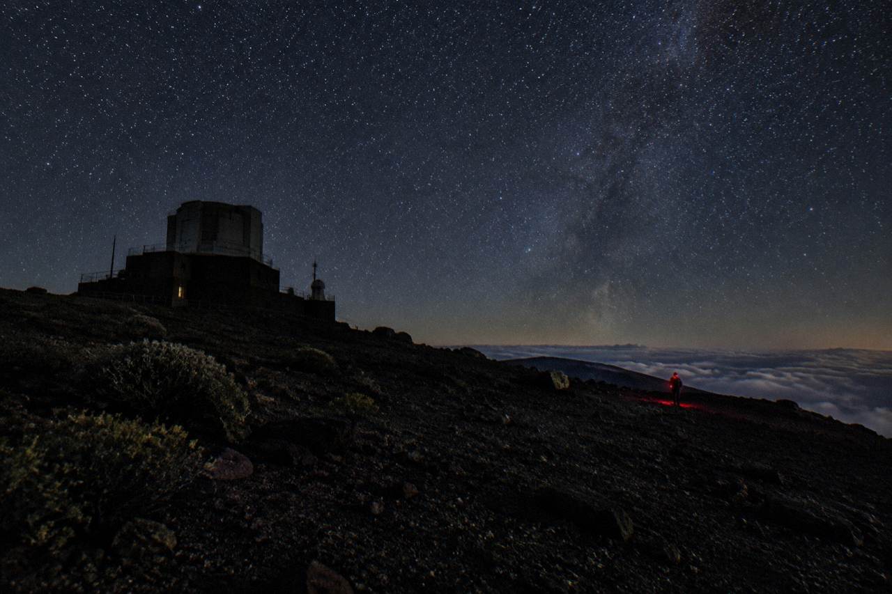 Night sky filled with stars above the dark silhouette of the Haleakala summit