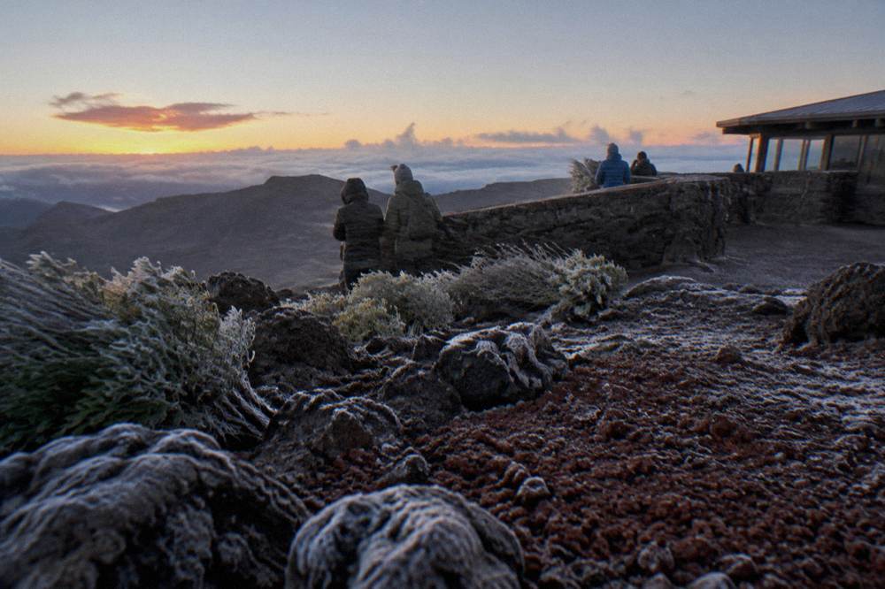 Visitors in winter jackets waiting at a windy summit overlook before sunrise