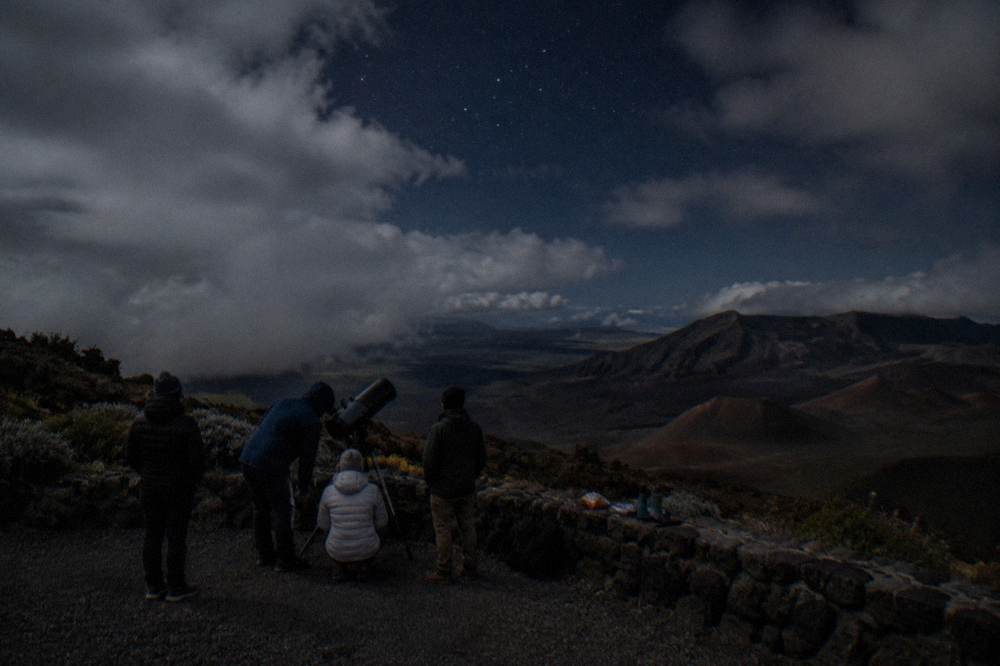 Group of people looking through a telescope under a starry sky at Haleakala