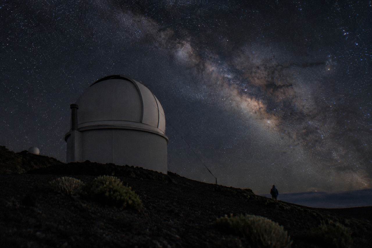 Starry night sky above Haleakala summit with silhouetted observatory dome