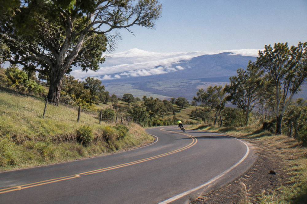 Riders coasting down a smooth paved highway through green upcountry slopes