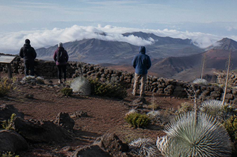 Cyclists in jackets and gloves pausing at a crater rim viewpoint