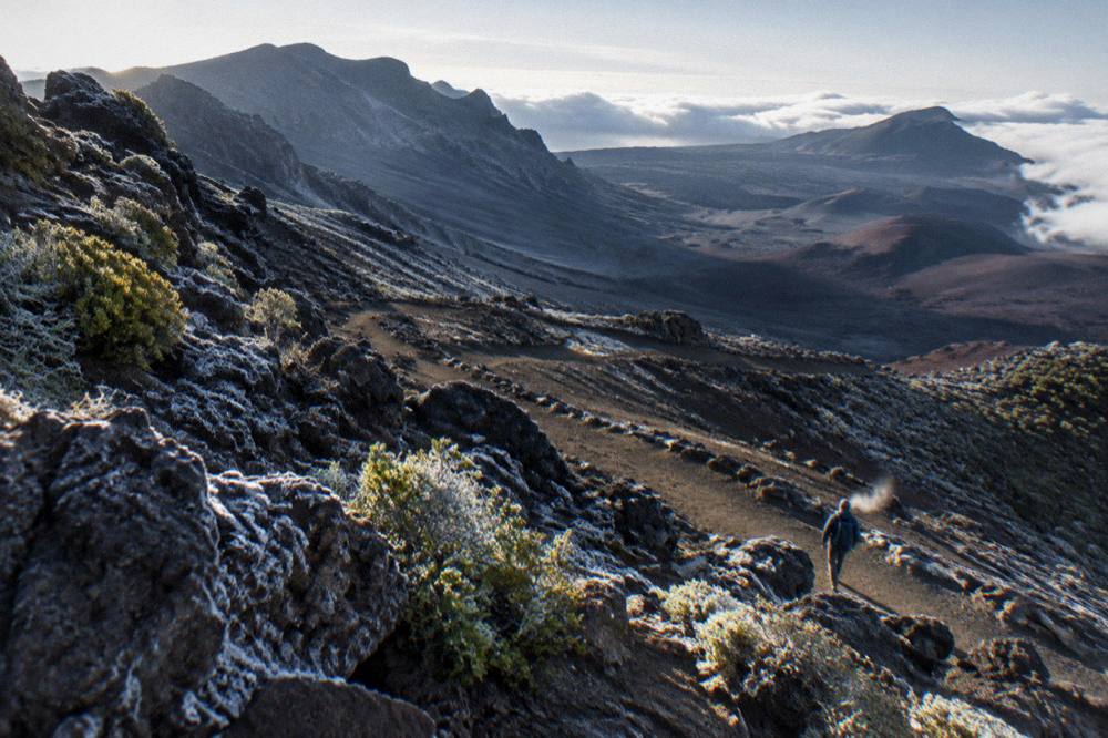 A crater trail curving downhill through scattered rocks under morning light