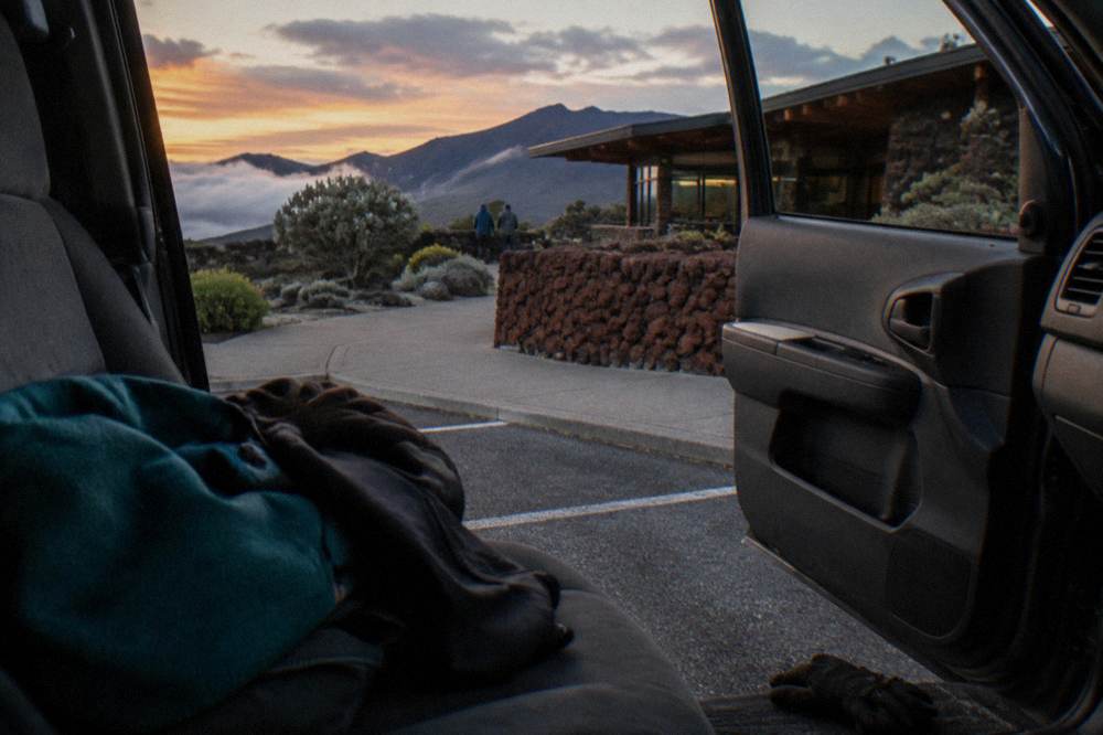 Warm jackets and gloves laid out on a car seat before a cold summit evening