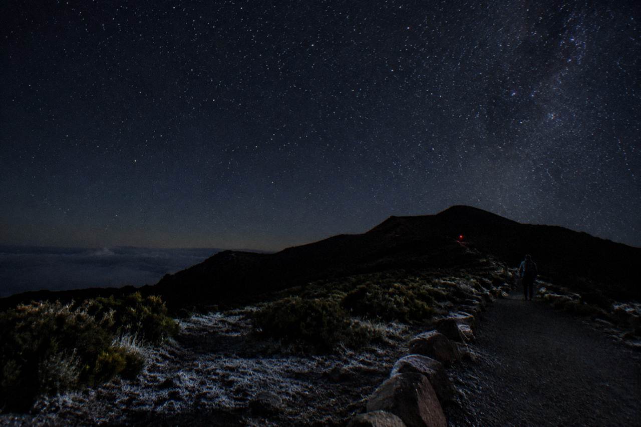 Night sky filled with stars above the dark silhouette of the Haleakala summit