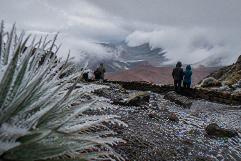 Warm-jacketed visitors standing at a windy high-elevation Haleakala overlook