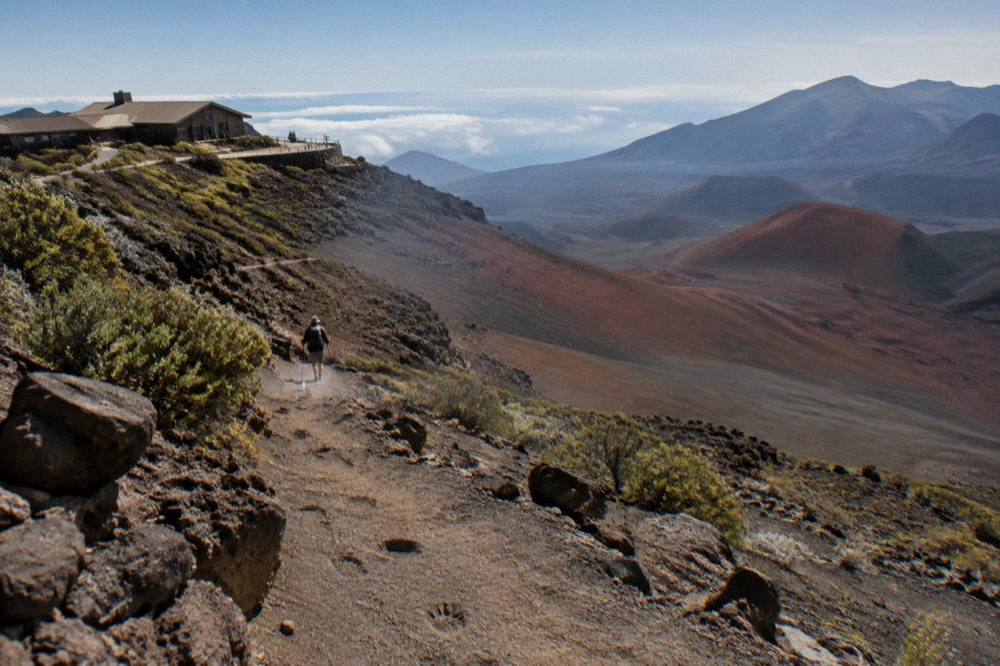 A trail dropping into a red and gray cinder basin below a high ridge