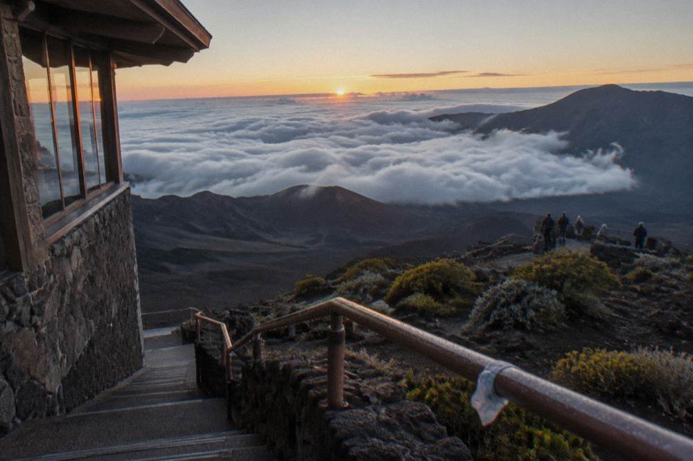 The Haleakala summit building and observation deck above a sea of clouds at dawn