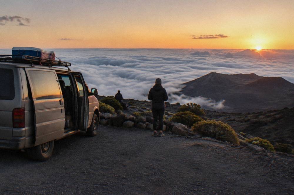 A tour van parked at a Haleakala overlook above the clouds at dusk