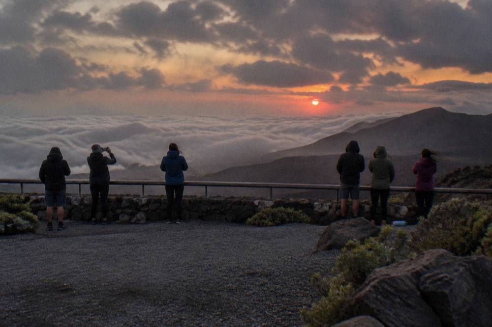 Visitors watching sunset from a crater overlook railing