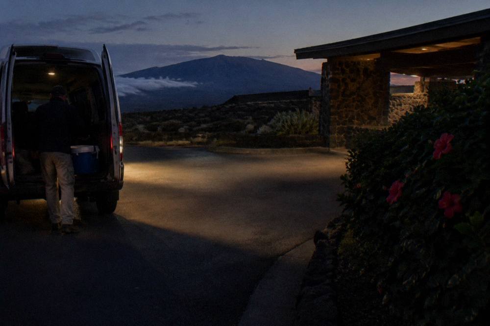 A tour van parked at a Kihei resort entrance in the early morning darkness