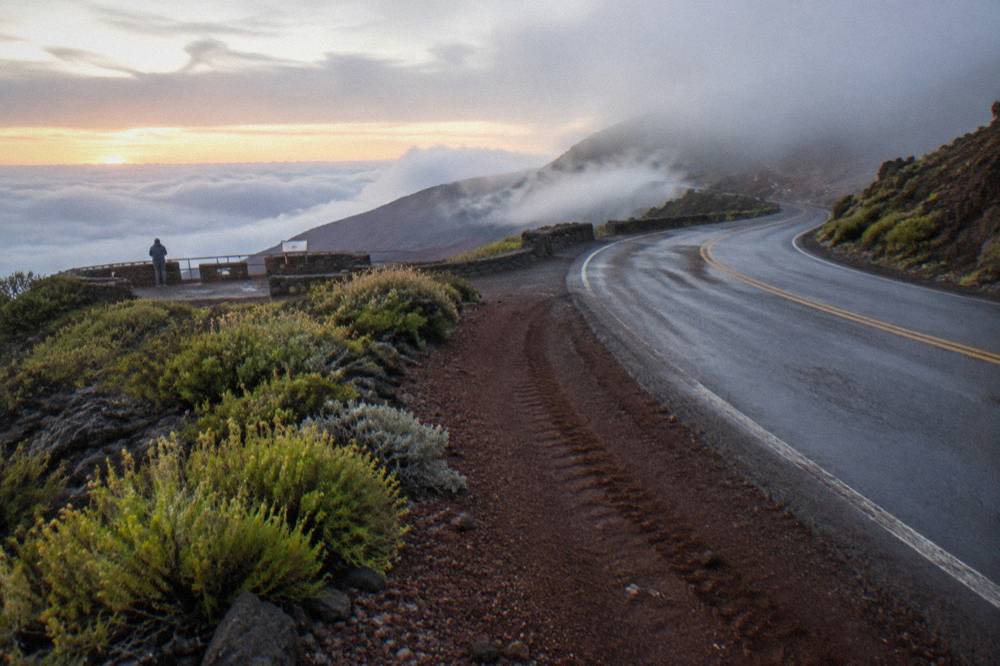 The winding crater road climbing through clouds toward the summit at dawn