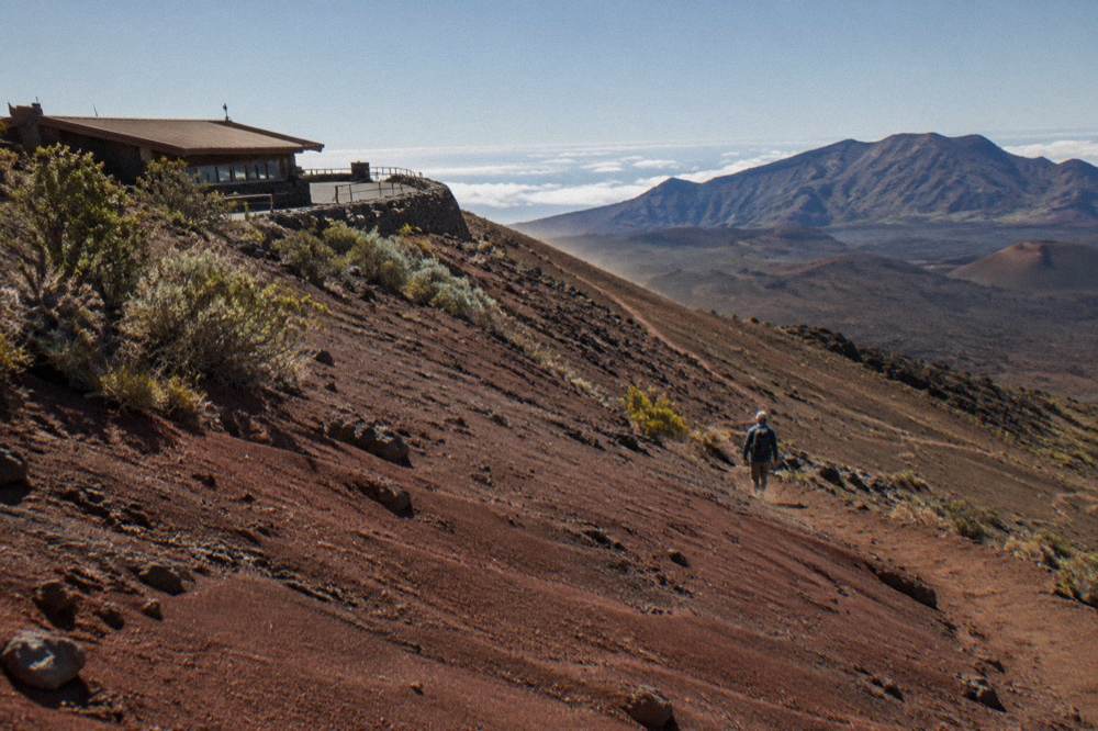 A hiker descending the cinder slope of the Sliding Sands trail into the crater