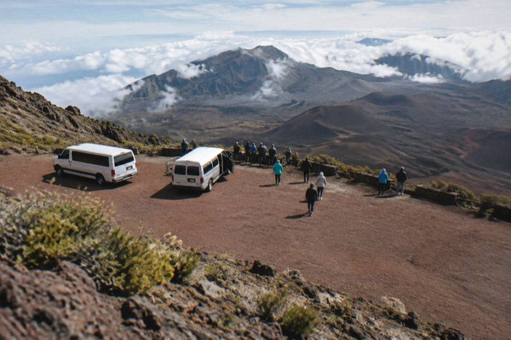Tour vans and visitors gathered at a crater rim overlook after sunrise