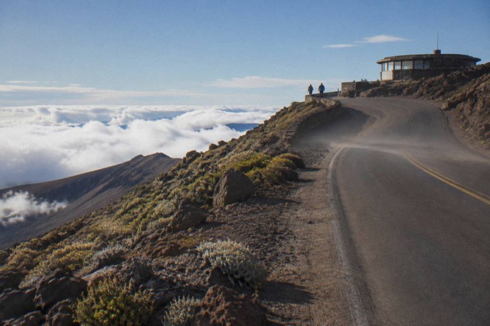 An empty crater road winding toward the summit above layered clouds