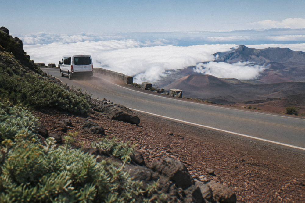 A van tour road curving up through open volcanic slopes above the clouds