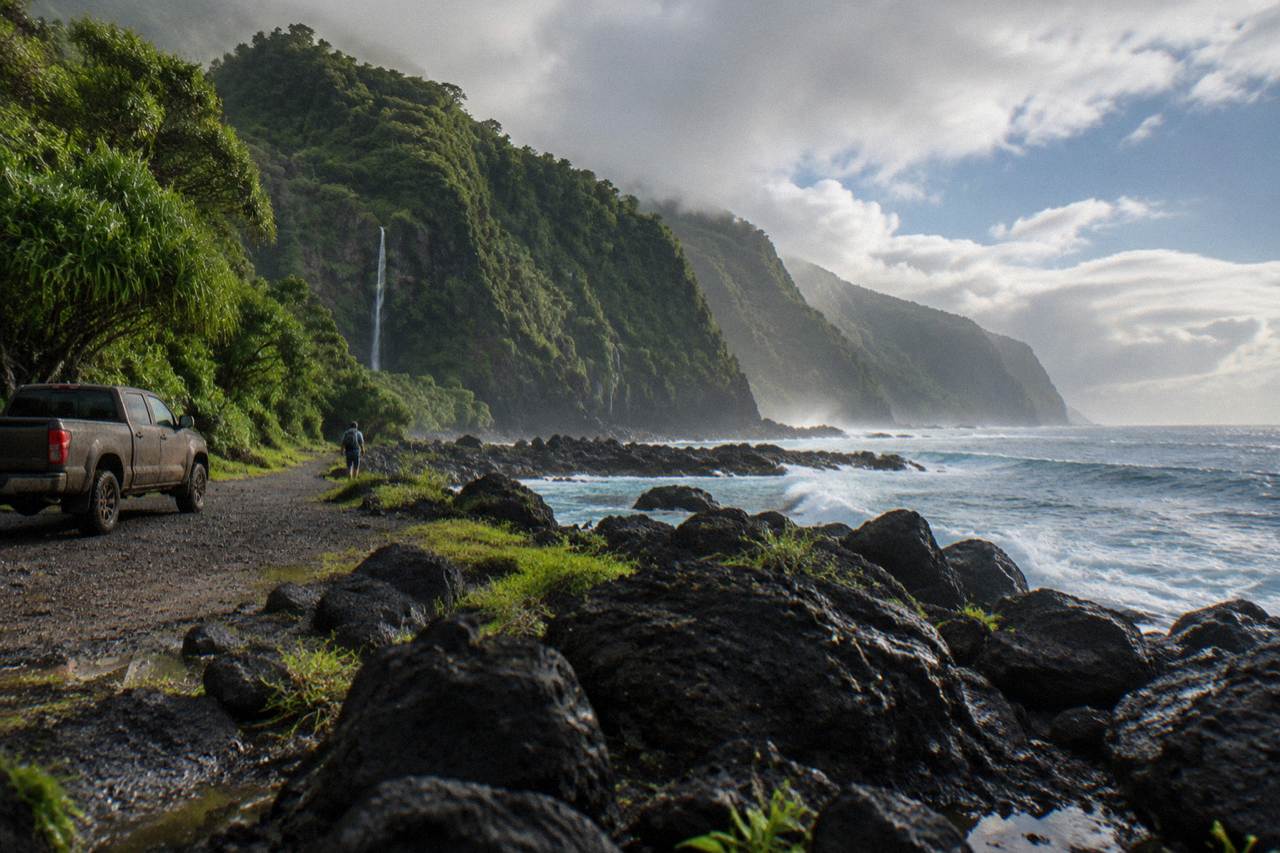 Winding coastal road along green sea cliffs with waterfalls in the distance