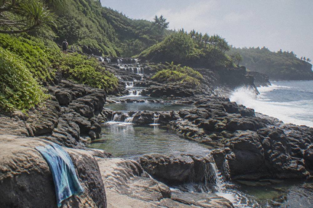 Freshwater pools spilling over terraced black lava rock toward the ocean