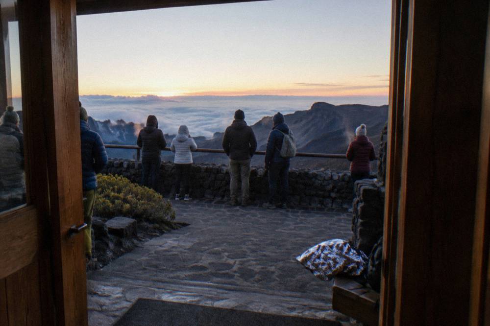 Visitors in warm jackets watching first light over the Haleakala crater rim