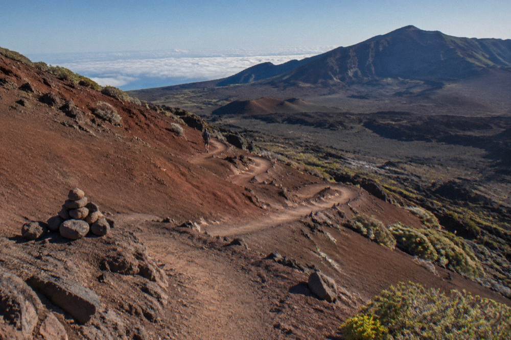 A marked trail descending between red cinder slopes into the crater